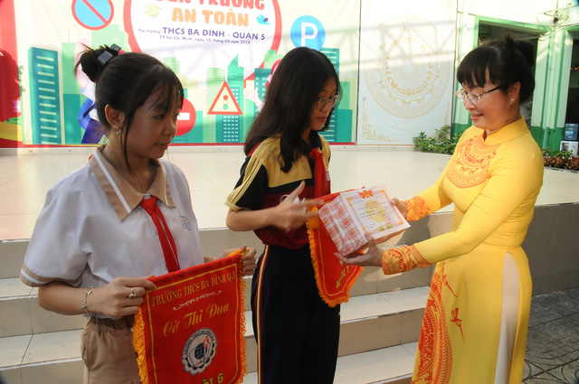 Cô Vương Thị Minh Xuân (hiệu trưởng trường THCS Ba Đình, quận 5) trao danh hiệu thi đua tuần cho đại diện các lớp. Ảnh: NGUYỄN HƯNG