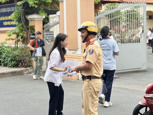 Tại các điểm thi, cảnh sát giao thông làm nhiệm vụ phân luồng, hỗ trợ tình nguyện viên tiếp sức mùa thi bê dụng cụ, tặng nước suối cho thí sinh - Ảnh: MAI TRÚC