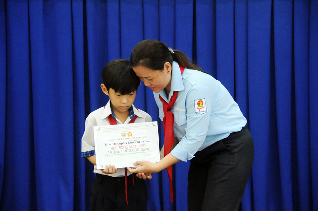 Chị Nguyễn Thị Ngọc Hiếu (phó chủ tịch Hội đồng Đội, phó Giám đốc Nhà thiếu nhi quận 10)  trao học bổng Vượt khó cho em Nguyễn Quang Mẫn, học sinh Trường Tiểu học Rạch Già, xã Hưng Long, huyện Bình Chánh trong chương trình Vì người bạn ngoại thành - Ảnh: NGUYỄN HƯNG