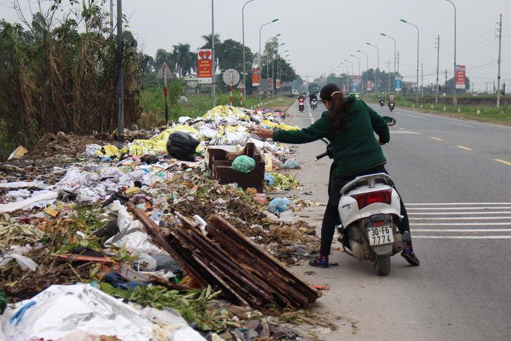 Hà Nội: Đổ trộm hàng đống rác ven quốc lộ, lấn nửa đường xe máy - Ảnh 2.