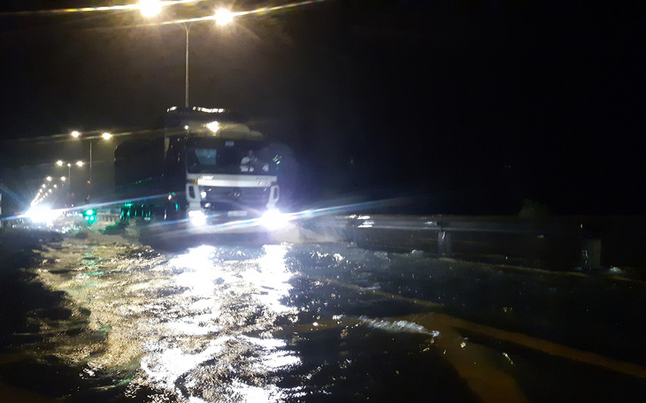 Nước lũ tràn qua quốc lộ 1 vào nhà dân, công an đội mưa điều tiết giao thông