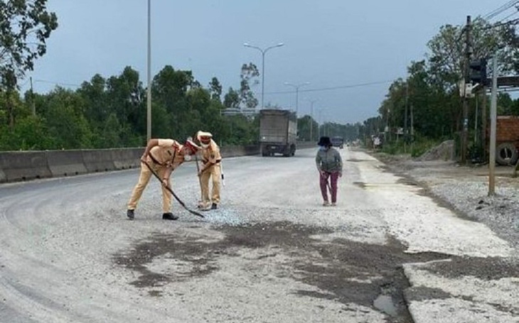 Cảnh sát giao thông dùng chổi, xẻng dọn dẹp đá dăm trên quốc lộ