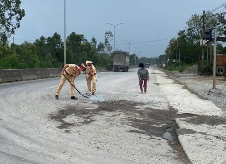 Cảnh sát giao thông dùng chổi, xẻng dọn dẹp đá dăm trên quốc lộ - Ảnh 1.