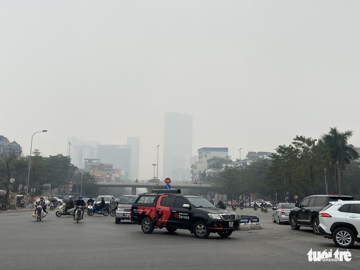 Sương mù giữa trưa Hà Nội, phải bật đèn chạy xe trên đường - Ảnh 1.