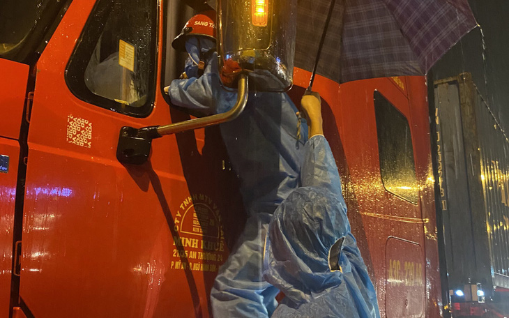Hình ảnh tình nguyện viên đội mưa, bám cabin kiểm soát xe trong đêm gây xúc động