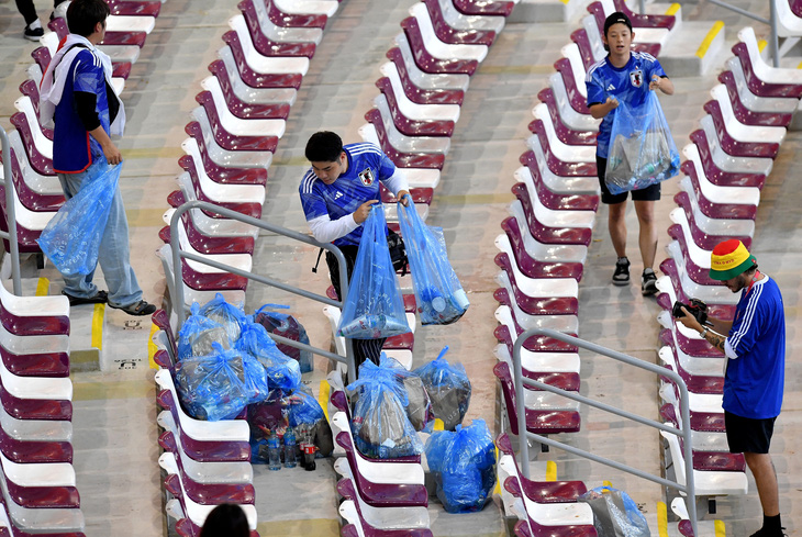 Cổ động viên Nhật Bản mang rác đựng trong túi nhựa khi họ dọn dẹp khán đài sau trận đấu Nhật Bản - Tây Ban Nha tại World Cup 2022 ở Qatar, ngày 2-12 - Ảnh: REUTERS
