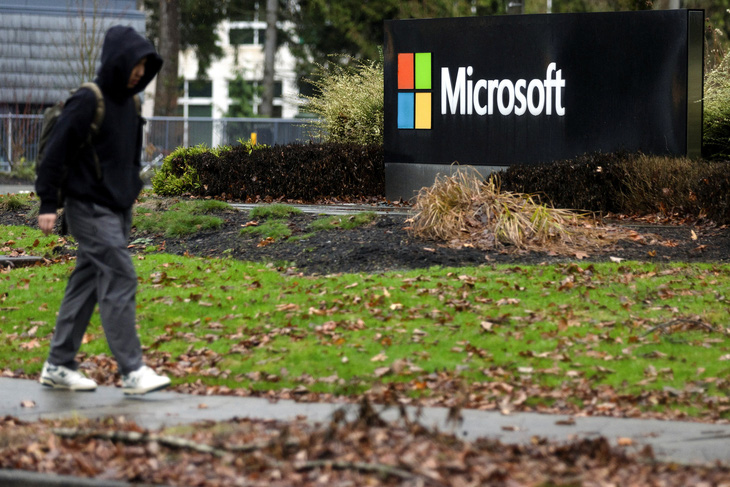 Một người đi ngang qua bảng tên của Microsoft tại trụ sở chính ở Redmond, Washington, Mỹ - Ảnh: REUTERS
