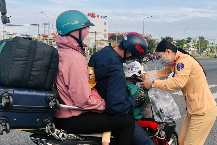Cảnh sát giao thông Đồng Nai tận tay đội nón bảo hiểm cho trẻ theo ba mẹ về quê đón Tết - Ảnh 1.