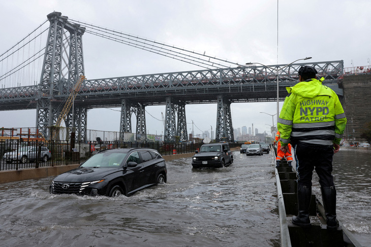 Cảnh sát New York quan sát ô tô đi qua con đường ngập nước, ngày 29-9 - Ảnh: REUTERS