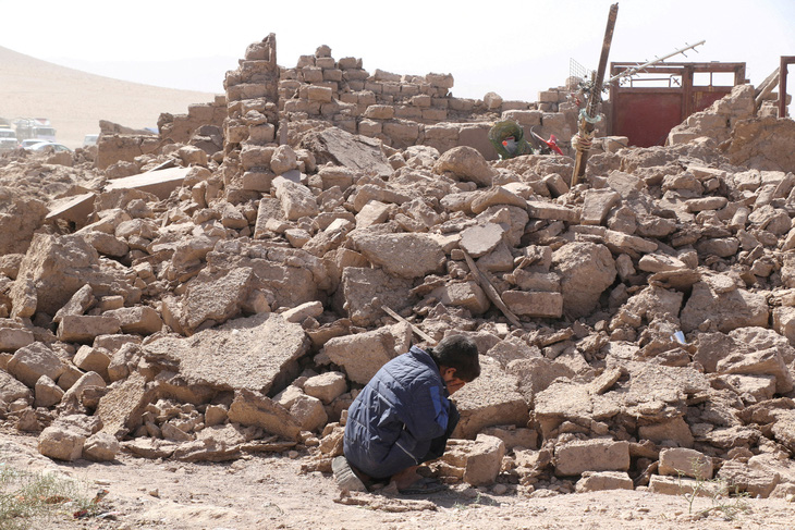 Cậu bé Afghanistan ôm mặt khóc cạnh đống đổ nát do động đất gây ra ở quận Zinda Jan, thành phố Herat hôm 8-10. Động đất liên hoàn xảy ra hôm 7-10 ở quốc gia khốn khổ này đã cướp đi mạng sống của hơn 2.400 người - Ảnh: REUTERS