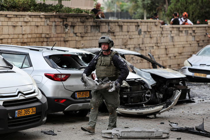 Cảnh sát Israel chuyển mảnh vỡ rocket bắn từ Dải Gaza vào Ashkelon, Israel ngày 9-10 - Ảnh: REUTERS