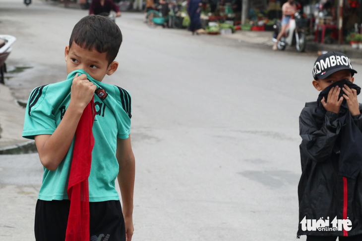 Các em học sinh đi học về phải bịt mũi vì mùi hôi thối do cá chết - Ảnh: DOÃN HÒA