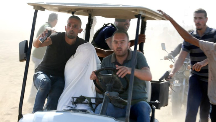Nhiều con tin (trùm khăn trắng) bị Hamas bắt giữ và đưa về Dải Gaza - Ảnh: WSJ