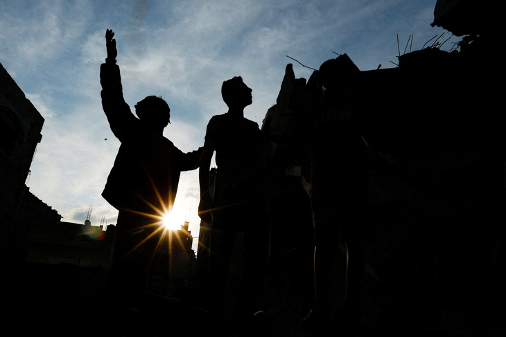 Người Palestine đứng cạnh đống đổ nát sau các cuộc tấn công của Israel tại Dải Gaza ngày 11-10 - Ảnh: REUTERS