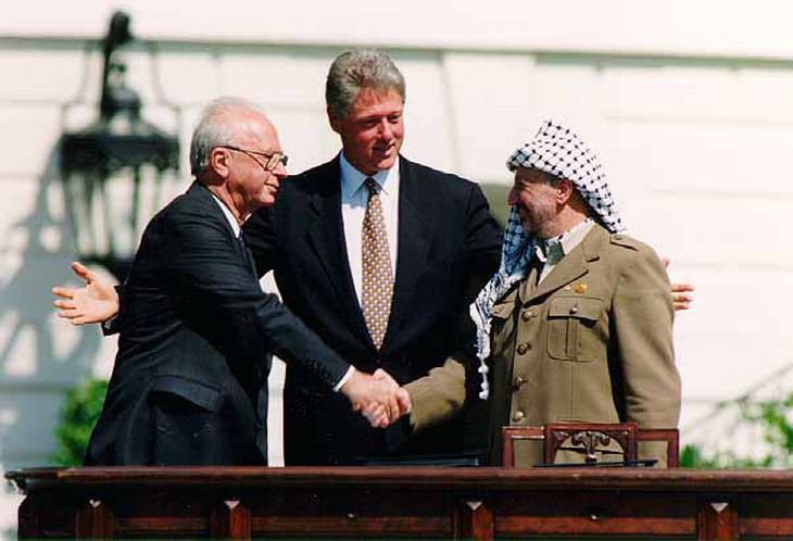Thủ tướng Israel Yitzhak Rabin (trái) bắt tay Chủ tịch Tổ chức giải phóng Palestine Yasir Arafat (phải) tại Lễ ký kết Hiệp định Oslo 1 ngày 13-9-1993 với sự chứng kiến của Tổng thống Mỹ Bill Clinton (giữa) - Ảnh: NHÀ TRẮNG
