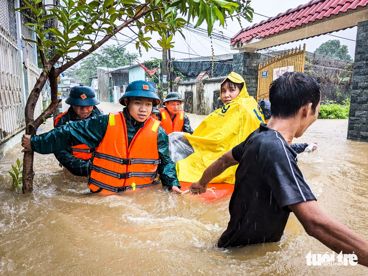 Bộ đội và cán bộ địa phương dầm mưa đưa mẹ con chị Tô Thị Hiếu (32 tuổi), trú kiệt 127 Mẹ Suốt, ra bên ngoài - Ảnh: TẤN LỰC