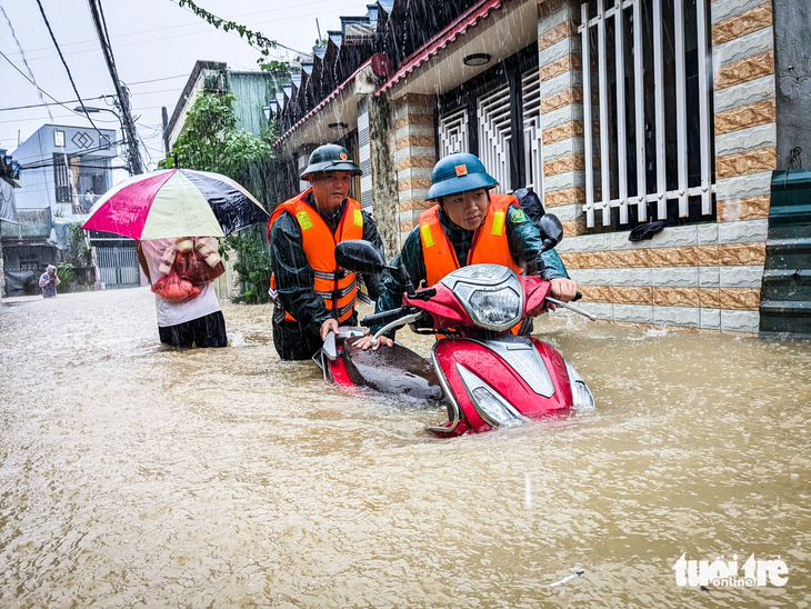 Dân quân giúp dân di dời xe máy ra khỏi vùng ngập lụt sâu tại phường Hòa Khánh Nam - Ảnh: TẤN LỰC