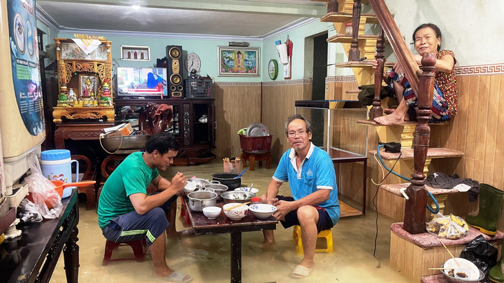 Bữa cơm trưa vội vã của gia đình ông Nguyễn Khôi (xã Lộc Trì, huyện Phú Lộc) trong nước lũ - Ảnh: BẢO PHÚ
