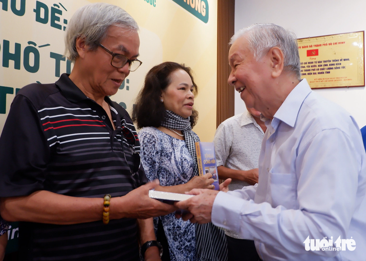 Ông Phạm Chánh Trực (bìa phải), trưởng ban tổ chức trại sáng tác, trao sách cho nhà văn Nguyễn Đông Thức - Ảnh: K.ANH