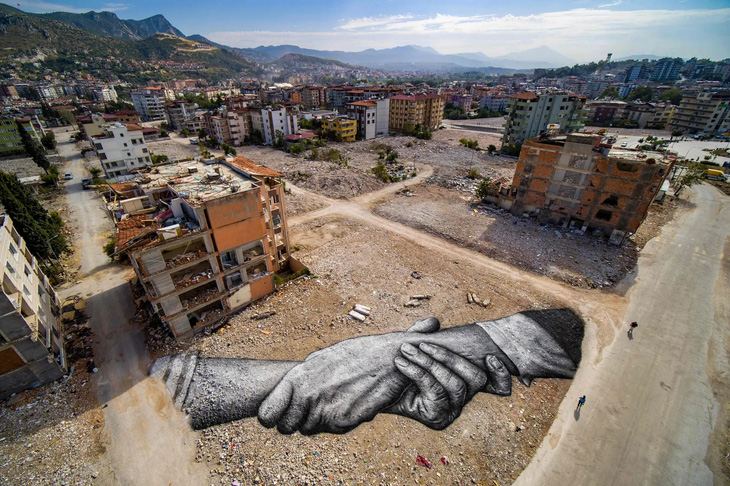 Bức tranh vẽ trên nền đất trống bên cạnh những tòa nhà từng bị phá hủy trong trận động đất ở tỉnh Hatay, Thổ Nhĩ Kỳ hồi tháng 2 năm nay của nghệ sĩ người mang hai dòng máu Pháp-Thụy Sĩ Guillaume Legros - Ảnh: AFP