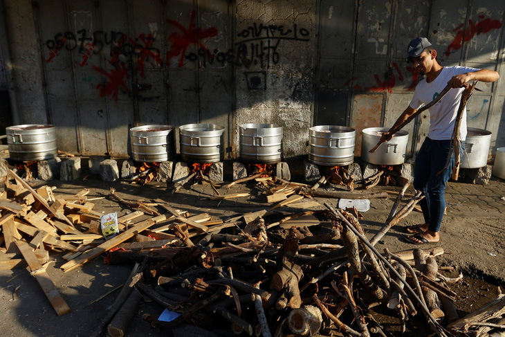 Người dân Palestine ở phía nam Dải Gaza nấu thức ăn bằng củi do bị cắt nguồn cung khí đốt - Ảnh: REUTERS