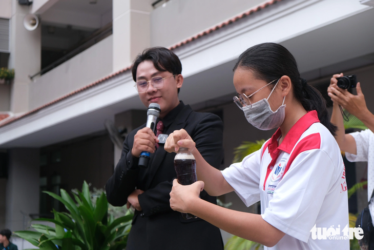 Em Trần Ngọc Anh (học sinh lớp 10A12, Trường THPT Nguyễn Hữu Thọ, quận 4) thực hành kiềm chế sự tức giận khi mở chai nước có gas - Ảnh: NGỌC PHƯỢNG