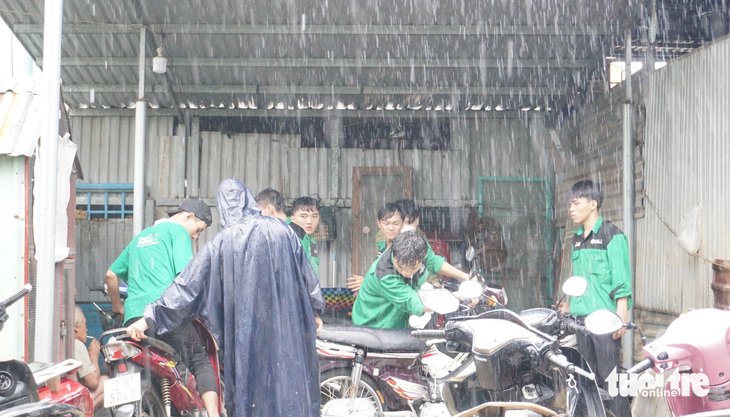 Dưới cơn mưa tầm tã, sinh viên sửa xe cho người dân ở điểm ngập lụt nặng của Đà Nẵng - Ảnh: ĐOÀN CƯỜNG
