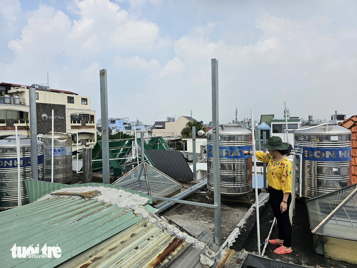 Phần công trình xây 'lụi' trên sân thượng nhà hàng xóm của bà Hồ Thị Sáu mới tháo dỡ một phần, vẫn còn các khung sắt - Ảnh: ÁI NHÂN