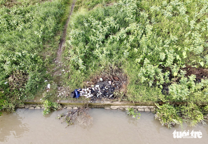 Vị trí xả rác thải y tế và đốt sát mép sông Sài Gòn. Khu vực này có nhiều cỏ lau, ít người qua lại. Nhiều chai lọ thủy tinh sau khi đốt nổ văng miểng hoặc rơi cả chai xuống lòng sông - Ảnh: CHÂU TUẤN