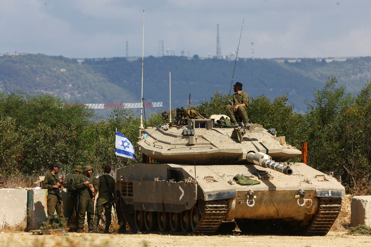 Binh sĩ Israel đứng cạnh xe tăng nằm gần biên giới Israel - Lebanon (phía bắc Israel) ngày 16-10 - Ảnh: REUTERS