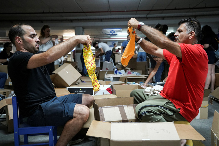 Các tình nguyện viên xếp quần áo trẻ em khi họ đóng gói các hộp hàng cứu trợ nhân đạo được quyên góp cho những người bị ảnh hưởng bởi cuộc tấn công của Hamas ở Tel Aviv, Israel, ngày 16-10 - Ảnh: REUTERS
