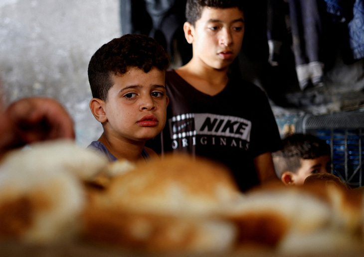 Những đứa trẻ Palestine nhìn bánh mì nướng trên lò củi trong bối cảnh thiếu nhiên liệu và điện tại Khan Younis ở phía nam Dải Gaza, ngày 16-10 - Ảnh: REUTERS