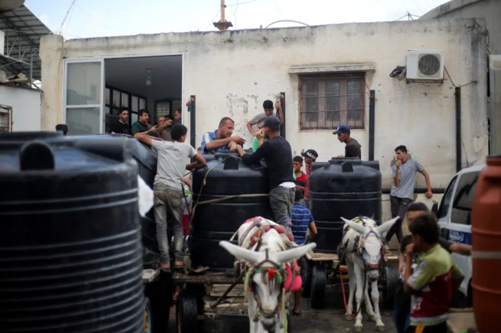 Cách người dân Palestine tại Dải Gaza lấy nước sau khi phía Israel cắt nguồn cung - Ảnh: REUTERS