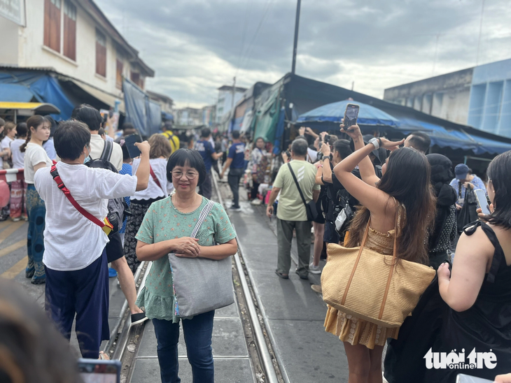 Du khách chụp hình trước chợ Maeklong ở Samut Songkhram, cách thủ đô Bangkok, Thái Lan hơn 70km về phía tây. Đây là điểm đến hấp dẫn cho những khách du lịch bụi muốn một lần trải nghiệm sự nguy hiểm - Ảnh: HẢI KIM