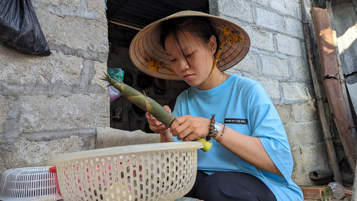 Cô sinh viên mồ côi Nguyễn Nữ Kiều Oanh (ngành ngôn ngữ Anh, Trường đại học Duy Tân, Đà Nẵng) cắt măng tre về nấu cho các em ăn - Ảnh: NHẬT LINH
