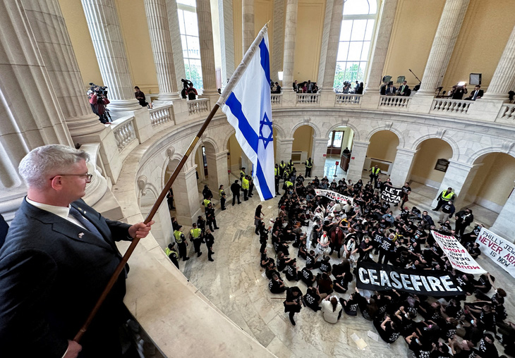 Dân biểu Cộng hòa Brandon Williams cầm cờ Israel trong lúc nhiều người biểu tình tràn vào tòa nhà văn phòng Hạ viện Cannon ở Washington D.C vào ngày 18-10 để kêu gọi lệnh ngừng bắn ở Gaza - Ảnh: REUTERS