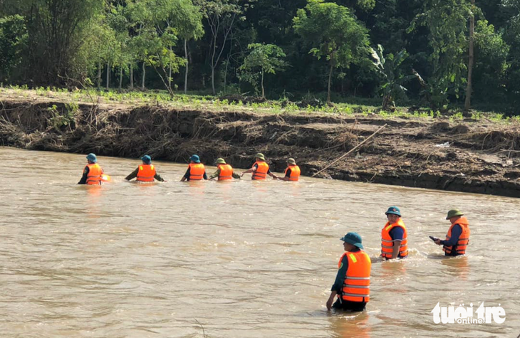 Lực lượng cứu hộ rà từng khúc sông tìm nam sinh lớp 10 bị lũ cuốn - Ảnh: HUY NHÂM