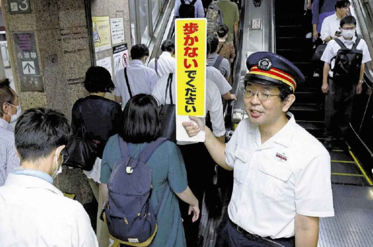 Một nhân viên ga tàu tại thành phố Nagoya nhắc nhở người dân di chuyển an toàn - Ảnh: ASIA NEWS NETWORK
