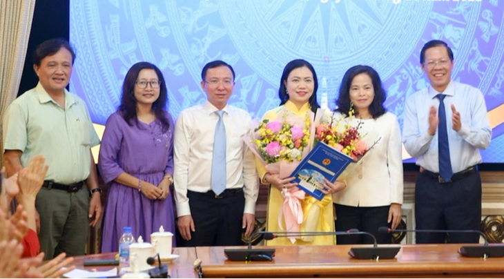 Chủ tịch UBND TP.HCM Phan Văn Mãi (bìa phải) cùng các đại biểu tặng hoa cho bà Vũ Thị Huỳnh Mai - Ảnh: L.H.