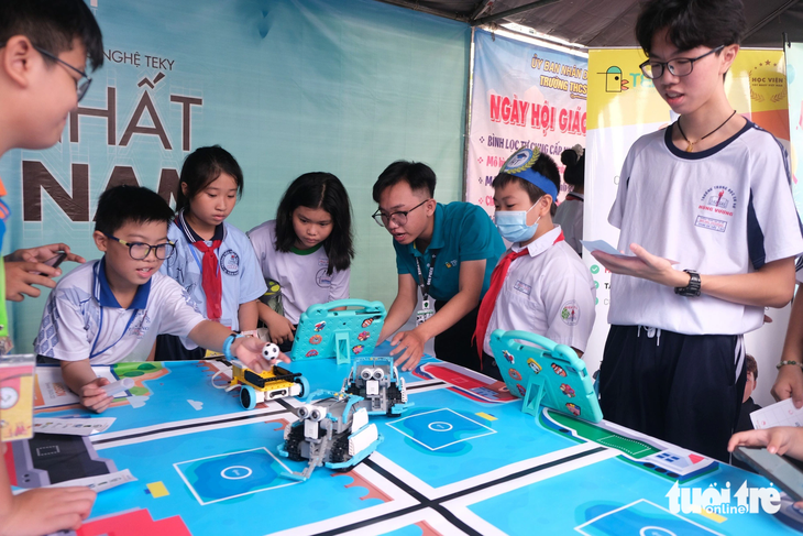 Các em học sinh trải nghiệm điều khiển robot tại ngày hội - Ảnh: NGỌC PHƯỢNG