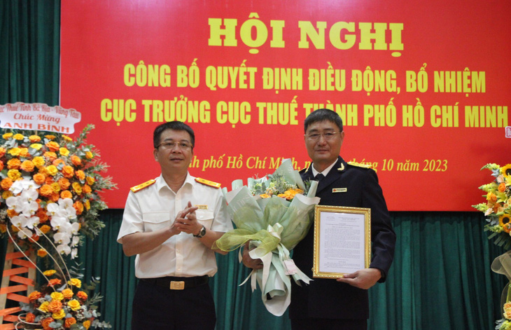 Ông Mai Xuân Thành (bìa trái), tổng cục trưởng Tổng cục Thuế, trao quyết định cho ông Nguyễn Nam Bình - Ảnh: A.H.