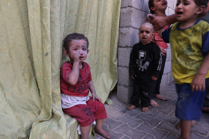 Trẻ em Palestine, bị phủ đầy bụi từ các cuộc không kích của Israel, đang ngồi trong một khu đất thuộc Bệnh viện Rafah, phía nam Dải Gaza ngày 23-10 - Ảnh: AFP