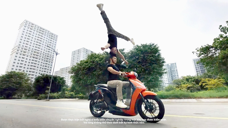 Nghệ sĩ Quốc Cơ - Quốc Nghiệp biểu diễn chồng đầu đi xe máy trong clip quảng cáo - Ảnh cắt từ clip