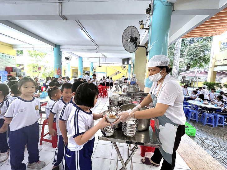 Học sinh Trường tiểu học Nguyễn Bình Khiêm, quận 1, TP.HCM, xếp hàng nhận suất ăn trưa 24-10 - Ảnh: MỸ DUNG