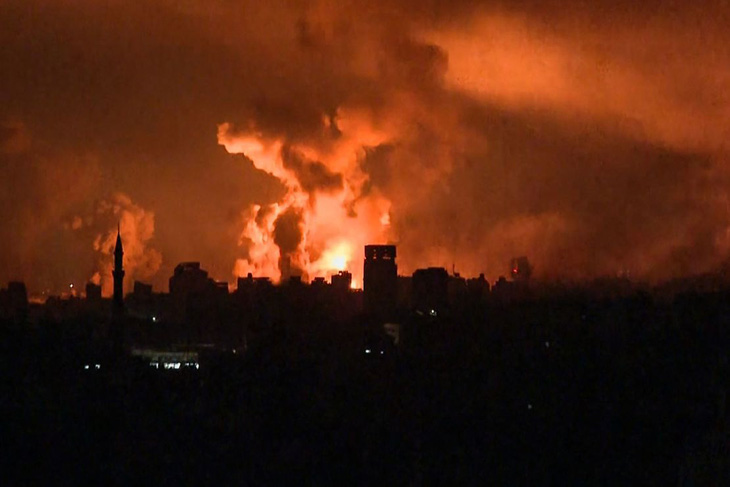 Lửa bốc cháy trên bầu trời Gaza sau đợt tấn công của Israel ngày 27-10 - Ảnh: AFP