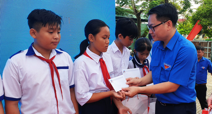 Anh Trần Hữu - ủy viên Ban thường vụ, trưởng Ban thanh niên công nhân và đô thị Trung ương Đoàn - trao quà cho các em học sinh có hoàn cảnh khó khăn - Ảnh: THANH HUYỀN