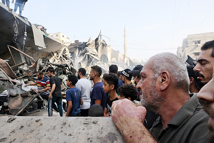 Người dân ở TP Gaza nhìn các tòa nhà bị đánh sập sau đợt không kích của Israel ngày 28-10 - Ảnh: AFP