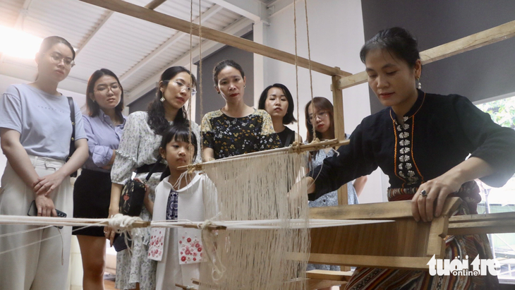 Nghệ nhân Sầm Thị Tình (37 tuổi, Nghệ An) hướng dẫn người tham dự dệt vải từ sợi gai dầu - Ảnh: THÁI THÁI