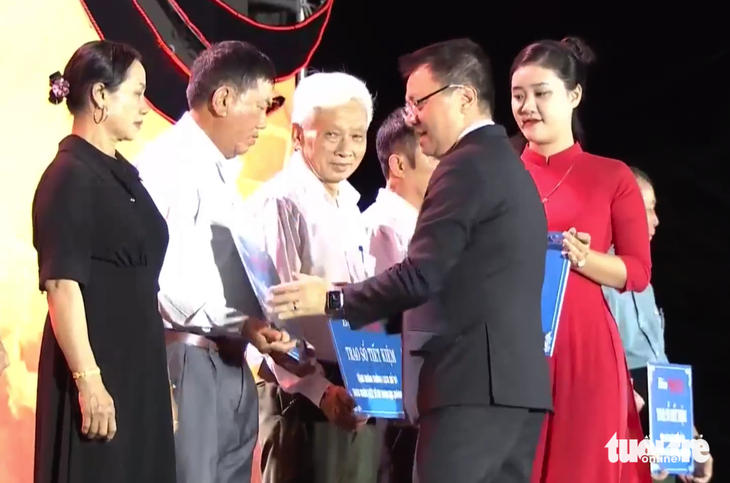 Ông Lê Quốc Minh, tổng biên tập báo Nhân Dân, trao sổ tiết kiệm cho thân nhân liệt sĩ TNXP Truông Bồn - Ảnh: DOÃN HÒA