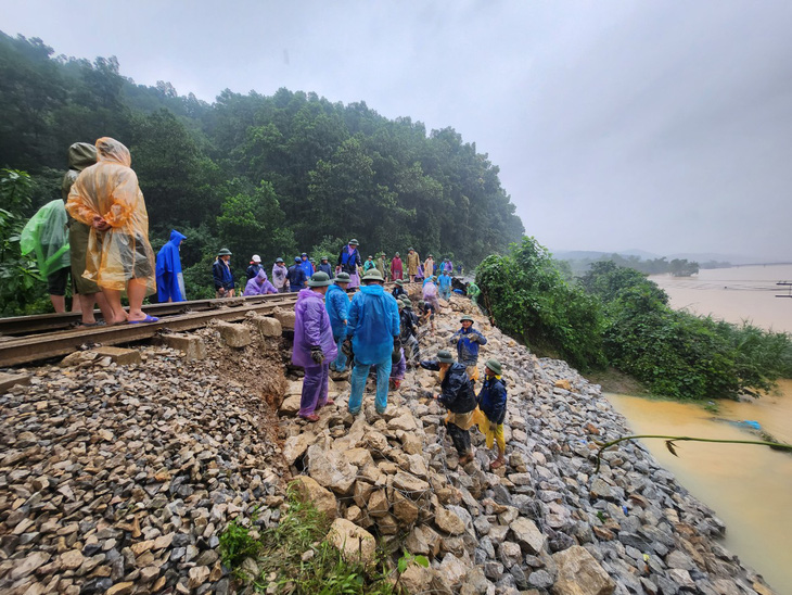Vị trí sạt lở nằm cạnh bờ sông Ngàn Sâu nên công nhân đường sắt chuyền tay từng viên đá để đắp lại nền đường - Ảnh: VNR